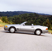 AUT 25 RK0232 01
1990 Mercedes-Benz 500SL Convertible Silver Profile View On Pavement Trees In Background Overcast
