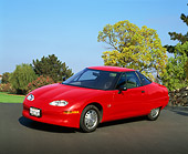 AUT 25 RK1172 03
1999 General Motors EV1 Electric Car Red 3/4 Front View On Pavement Trees Blue Sky