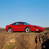 AUT 25 RK0602 01
1991 Dodge Stealth Red 3/4 Low Side View By Dirt Cliff Blue Sky