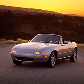 AUT 25 RK0767 03
1990 Mazda Miata Convertible Silver 3/4 Front View On Pavement Hills Background At Dusk