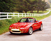 AUT 25 RK1408 01
1990 Mazda Miata Convertible Red With Flames Front 3/4 View On Pavement By White Fence