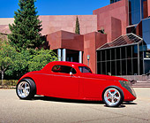 AUT 26 RK0414 03
1937 Ford Coupe Red 3/4 Front View On Pavement By Museum And Trees