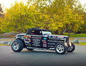 AUT 26 RK2921 01
1932 Ford Roadster Hot Rod Black With Decals 3/4 Front View On Pavement By Trees