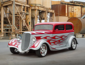 AUT 26 RK3356 01
1933 Ford Sedan Red And Silver With Flames 3/4 Front View On Pavement By Old Factory