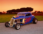 AUT 26 RK0340 01
1934 Ford 3-Window Coupe Blue With Flames 3/4 Front View On Gravel Trees And Grass Filtered