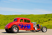 AUT 26 RK1250 01
1934 Chevrolet 5-Window Coupe Hot Rod Red With Blue Flames 3/4 Rear View By Grass Hill Blue Sky
