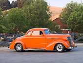 AUT 26 RK1306 01
1938 Chevrolet Coupe Hot Rod Orange 3/4 Front View By Trees