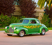 AUT 26 RK2664 01
1940 Chevrolet Coupe Hot Rod Green With Yellow Flames 3/4 Front View On Pavement By Shrubs And Trees
