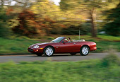 AUT 29 RK0040 19
1997 Jaguar XK8 Convertible Red 3/4 Side View On Road In Motion By Trees