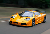 AUT 29 RK0124 16
1996 McLaren F1 LM Orange In Motion 3/4 Front View On Road By Grass And Trees