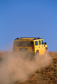 AUT 29 RK0618 06
2003 GM H2 Hummer Yellow 3/4 Rear View On Dirt Hill In Motion Blue Sky Making Dust