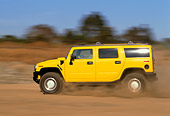 AUT 29 RK0620 02
2003 GM H2 Hummer Yellow Profile View On Dirt Road In Motion Blue Sky