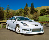 AUT 33 RK0291 01
2000 Toyota Celica Custom Sky Blue 3/4 Front View On Pavement By Trees And Grass Hills