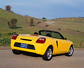 AUT 33 RK0145 01
2000 Toyota MR2 Spyder Yellow 3/4 Rear View On Pavement By Grass Hills