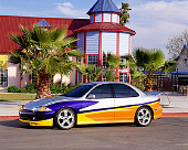AUT 34 RK0359 04
2001 Chevrolet Cavalier Silver And Yellow 3/4 Front View On Pavement By Building Palm Tree