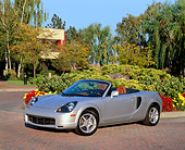 AUT 35 RK0270 02
2002 Toyota MR2 Convertible Silver 3/4 Front View By Flowers Bushes And Trees