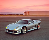 AUT 38 RK0237 02
2003 GSR Noble M12 GTO Silver 3/4 Front View On Pavement Airplane Hanger Background Filtered