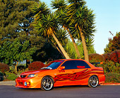 AUT 38 RK1864 02
2003 Mazda Protege Orange With Red Flames Custom 3/4 Front View On Pavement By Palm Trees