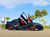 AUT 39 RK0406 01
2004 Mazda RX-8 Custom Black 3/4 Front View Doors Open On Pavement By Trees Blue Sky