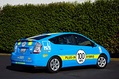AUT 41 RK0552 01
2006 Toyota Prius Plug-In Hybrid Blue With Yellow Stripes 3/4 Rear View On Pavement By Shrubs
