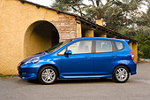 AUT 42 RK0067 01
2007 Honda FIT 5DR Sport Blue 3/4 Side View On Pavement By Building