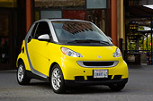 AUT 43 RK0111 01
2008 Smart Fortwo Yellow 3/4 Front View On Pavement By Building