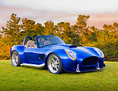 AUT 45 BK0004 01
2010 Iconic AC Roadster Blue 3/4 Front View On Grass By Trees