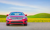 AUT 46 BK0048 01
2011 Ford Fusion Hybrid Red Front View On Pavement By Field Of Wildflowers