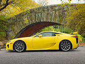 AUT 48 RK0019 01
2012 Lexus LFA Coupe Yellow Profile View On Pavement By Trees And Stone Bridge