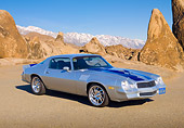 CAM 01 RK0238 01
1978 Chevrolet Camaro Z-28 Silver With Blue Stripe 3/4 Front View On Pavement By Rocks And Snowy Peaks