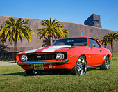 CAM 02 RK0182 01
1969 Chevrolet Camaro SS Red With White Stripes 3/4 Front View On Grass By Palm Trees And Building