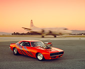 CAM 03 RK0101 02
1968 Chevy Camaro Prostreet Orange Purple Graphics 3/4 Side View On Pavement Airplane In Background