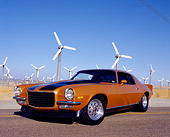 CAM 04 RK0067 01
1973 Chevrolet Camaro Gold Black Stripe Low 3/4 Front View On Road By Wind Turbines