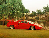 LAM 01 RK0170 02
1989 Lamborghini Countach 25th Anniversary Red 3/4 Front View On Grass By Water And Trees At Dusk