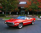 MST 03 RK0133 02
1969 Shelby GT350 Convertible Orange With White Stripe 3/4 Front View On Pavement By Building