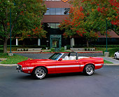 MST 03 RK0134 02
1969 Shelby GT350 Convertible Orange With White Stripe 3/4 Side View On Pavement By Building