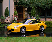 POR 01 RK0021 01
2001 996 Twin Turbo Porsche Yellow 3/4 Side View On Wet Pavement By House With Lion Statue