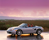 POR 04 RK0198 02
1998 Porsche Boxster Convertible Silver 3/4 Side On Wet Pavement By Tall Grass Headlights On At Dusk