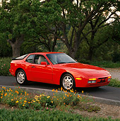 POR 04 RK0252 06
1990 Porsche 944 Turbo Red Side 3/4 View On Pavement By Flowers And Trees Parking Lights On