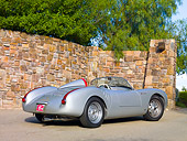 POR 06 RK0028 01
1955 Porsche 550 Spyder Silver 3/4 Rear View On Pavement By Stone Wall
