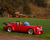 POR 07 RK0030 02
1989 Porsche 911 Speedster Anniversary Red 3/4 Side View On Grass Old House In Back