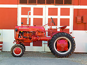 TRA 01 RK0138 01
1957 McCormick Cub Tractor Red Profile View On Gravel By Barn
