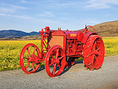 TRA 01 RK0142 01
1918 Avery Model B Tractor Orange 3/4 Front View On Gravel By Field Of Wildflowers