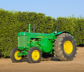 TRA 01 RK0167 01
1955 John Deere 80 Green And Yellow 3/4 Side View On Dirt By Shrubs