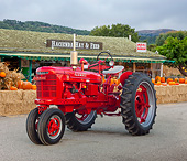 TRA 01 RK0200 01
1944 Farmall H Tractor Red With 27V Mower 3/4 Front View On Pavement By Feed Store And Pumpkins