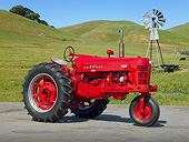 TRA 01 RK0211 01
1955 Farmall 400 Tractor Red 3/4 Side View On Pavement Grassy Hills And Windmill