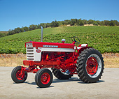 TRA 01 RK0214 01
1958 Farmall 560 Tractor Red And White 3/4 Side View On Gravel By Crops