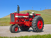 TRA 01 RK0224 01
1970 International 1456 Tractor Red 3/4 Side View On Gravel By Grassy Hills And Windmills