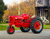 TRA 01 RK0276 01
1954 Farmall Super MTA Tractor Red 3/4 Side View On Gravel By Water Tower And Autumn Trees