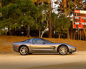 VET 01 RK0581 03
2003 Chevrolet Corvette Coupe Gray Low Profile View On Sand By Trees And Football Scoreboard